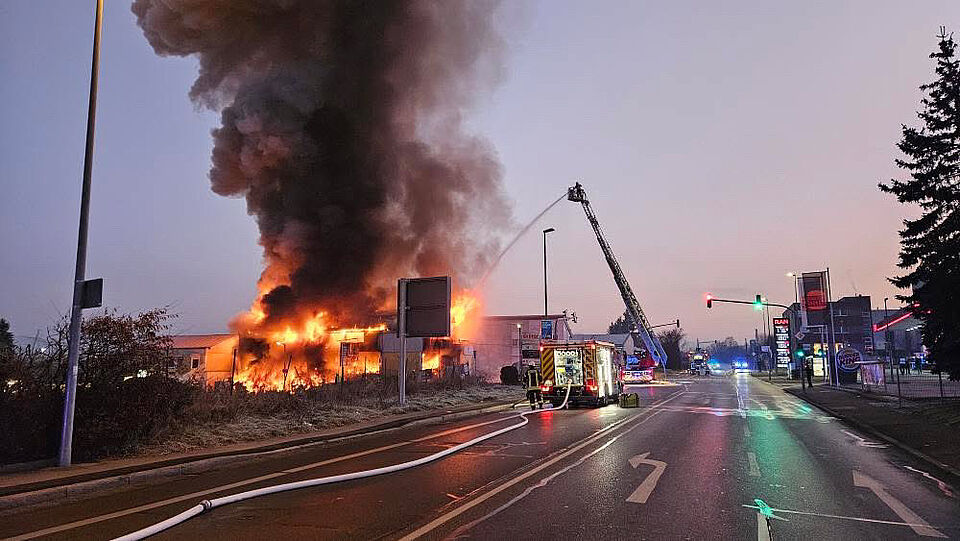 Brennendes Gebäude mit Feuerwehrfahrzeugen