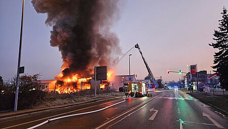 Brennendes Gebäude mit Feuerwehrfahrzeugen